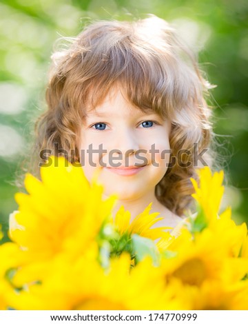 Happy child with bouquet of beautiful sunflowers against green background. Spring family holiday concept. Mother`s day