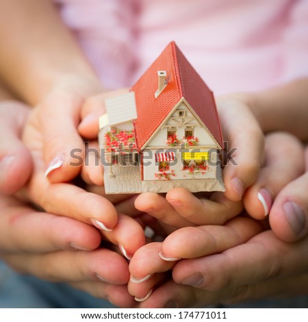 Family holding little house in hands. Real estate concept