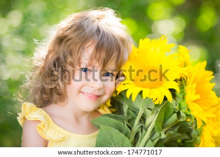 Happy child with bouquet of flowers against green background. Spring family holiday concept. Mother`s day