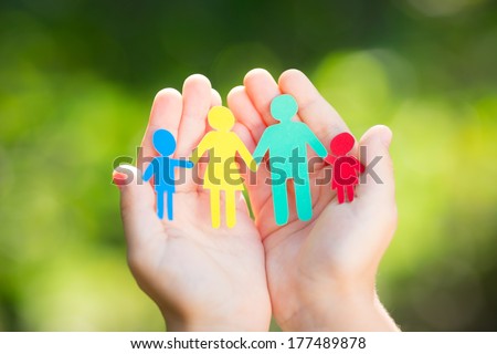 Child holding paper family in hands against spring green background