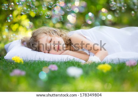 Happy kid sleeping on green grass outdoors in spring garden Happy kid sleeping on green grass outdoors in spring garden