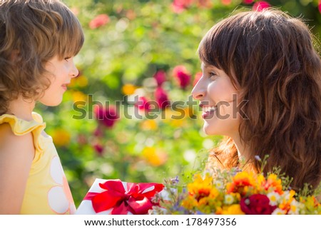 Woman and child with bouquet of flowers against green background. Spring family holiday concept. Mother`s day