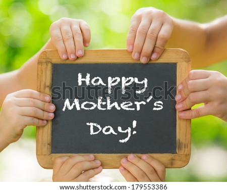 Many hands holding blackboard against spring green background. Mother\'s day greeting concept