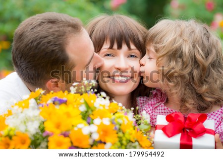 Happy family with bouquet of flowers against green background. Spring holiday concept. Mother\'s day