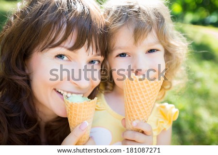 Happy child and mother eating ice-cream outdoors in summer park
