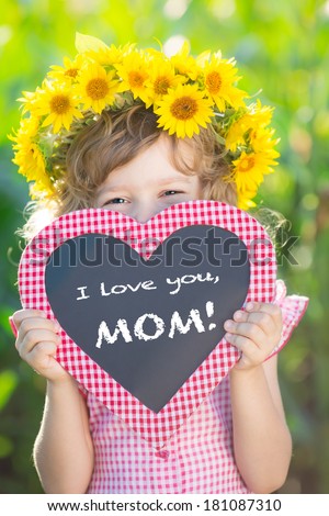Child holding blackboard against green background. Spring family holiday concept. Mother\'s day