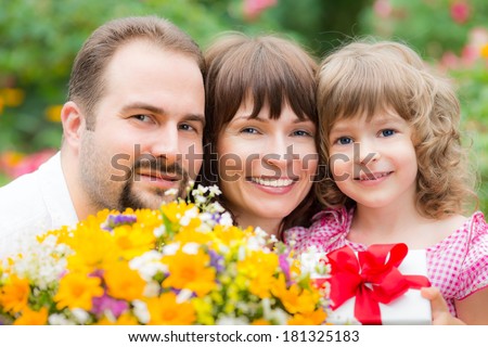 Happy family with bouquet of flowers against green background. Spring holiday concept. Mother\'s day