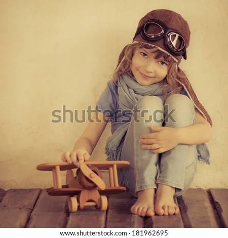 Happy kid playing with toy wooden airplane indoors Retro toned Happy kid playing with toy wooden airplane indoors Retro toned