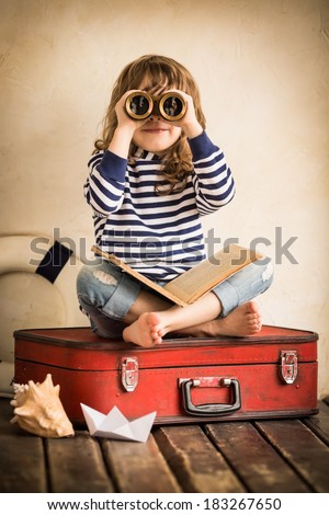 Funny kid playing with toy sailing boat indoors. Travel and adventure concept
