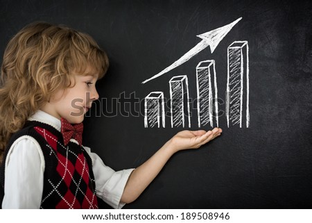 Smart kid in class. Happy child against blackboard. Drawing growth bar graph