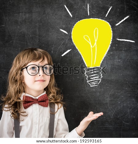 Smart kid in class. Happy child against blackboard. Drawing light bulb. Business idea concept