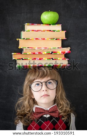 Smart kid in library. Schoolchild with textbooks and green apple against blackboard. Education concept