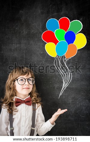 Smart kid in class. Happy child against blackboard with drawing colored balloons. Education concept