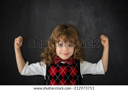 Strong kid in class. Happy child against blackboard. Education concept