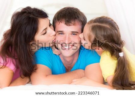 Woman and child kissing young man. Happy family having fun at home. Fathers day