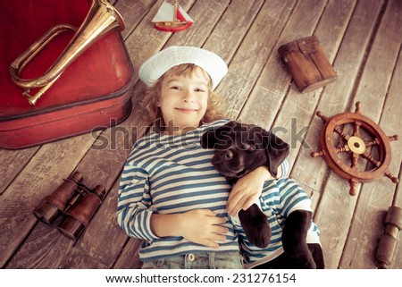 Happy kid dressed in sailor. Child playing with dog at home. Travel and adventure concept