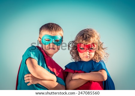 Superhero children against summer sky background. Kids having fun outdoors. Boy and girl playing. Success and winner concept