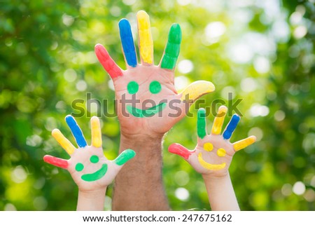 Smiley on hands against green spring blurred background. Family having fun outdoors