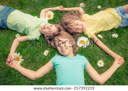 Happy children lying on grass. Funny kids playing in park. Beautiful spring flowers