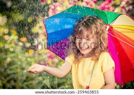Happy child in the rain. Funny kid playing outdoors in spring park