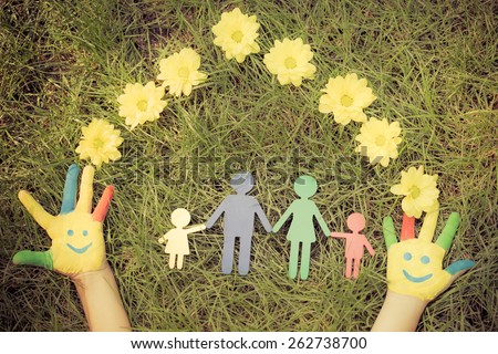 Group of happy people on green grass. Family having fun in spring. Smiley on hands. Ecology concept. Top view portrait. Retro toned image