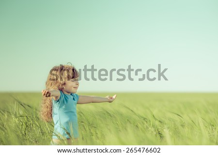 Happy child in spring field. Young girl relax outdoors. Freedom concept