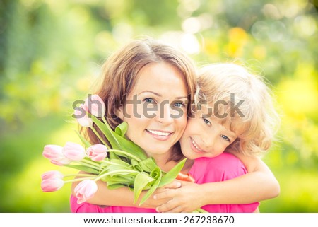 Mother and daughter with bouquet of flowers against green blurred background. Spring family holiday concept. Mother\'s day