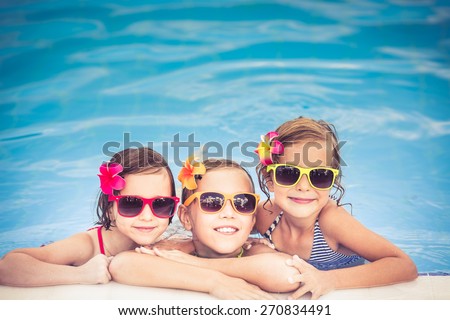 Happy children in the swimming pool. Funny kids playing outdoors. Summer vacation concept