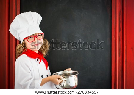 Child chef cook against blackboard blank menu with drawing healthy food. Restaurant business concept