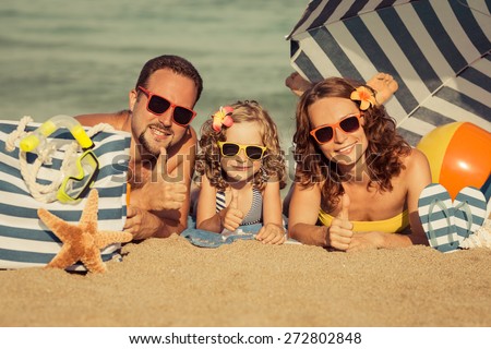 Happy family lying on the beach. People showing thumbs up. Summer vacation concept. Retro toned image
