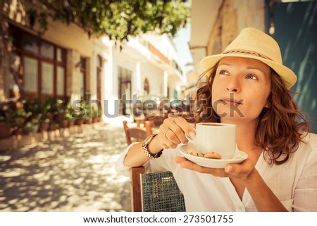 Young beautiful woman drinking coffee in summer cafe outdoors