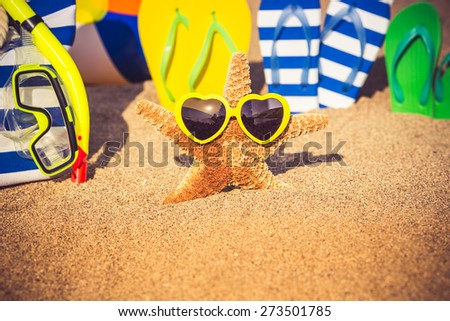 Flip-flops, beach bag and funny starfish on the sand. Summer family vacation concept
