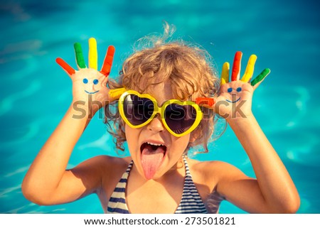 Funny child with drawing smiley on hands in swimming pool. Summer vacation concept