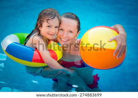 Happy child and woman playing in swimming pool. Summer vacation concept
