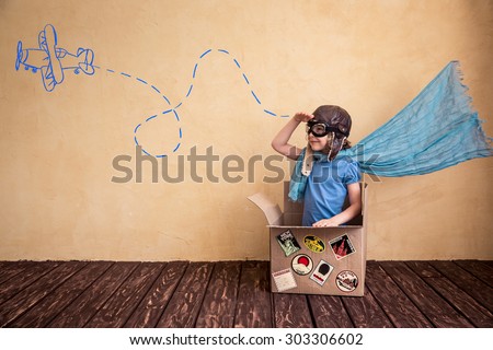 Happy child playing in cardboard box. Kid having fun at home