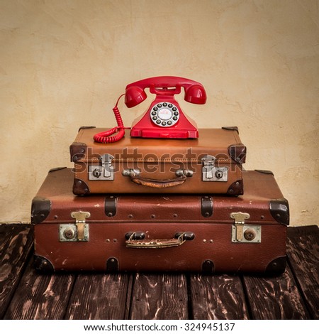 Vintage classic brown leather suitcase and retro phone. Travel agency business concept