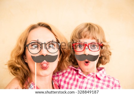 Mother and child with fake mustache. Happy family playing in home