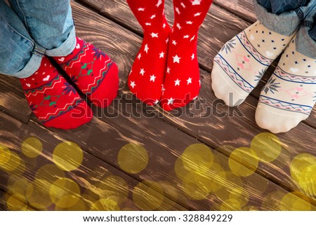 Feet wearing Christmas socks on wood floor. Happy family at home. Xmas holidays concept
