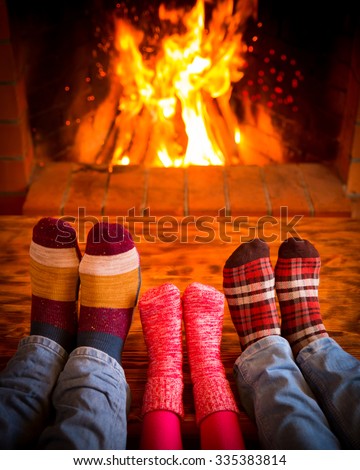 Family relaxing at home. Feet in Christmas socks near fireplace. Winter holiday concept