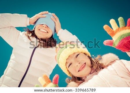 Happy family having fun outdoors in winter against blue sky background. Low angle view selfie