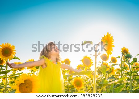 Happy child having fun in spring field against blue sky background. Freedom concept