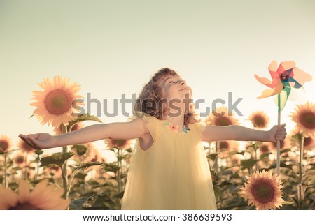 Happy child having fun in spring field against blue sky background. Freedom concept
