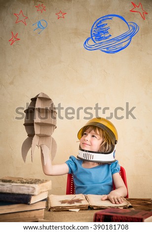 Child astronaut with cardboard toy rocket. Child playing at home. Earth day concept