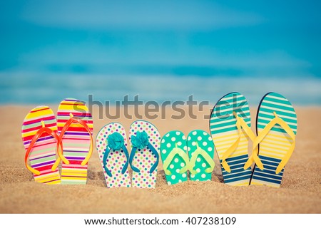 Flip-flops on sandy beach against blue sea and sky background. Summer vacation concept