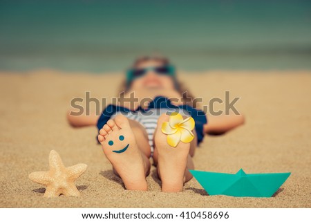 Child lying on sandy beach near blue sea. Summer vacation and healthy lifestyle concept