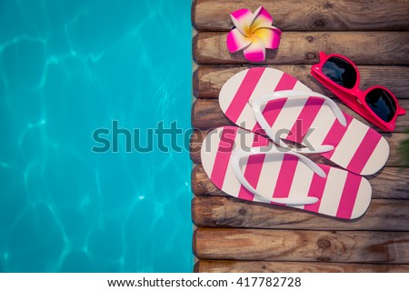 Flip-flops on wood against blue water background. Summer holiday concept