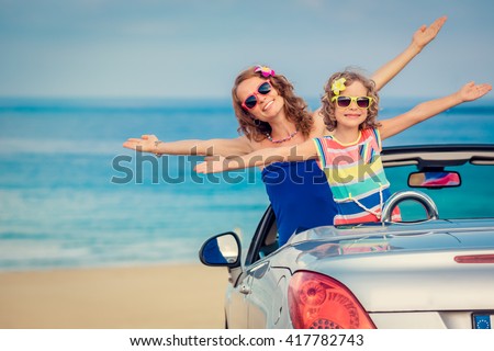 Happy family travel by car to the sea. Woman and child having fun in cabriolet. Summer vacation concept