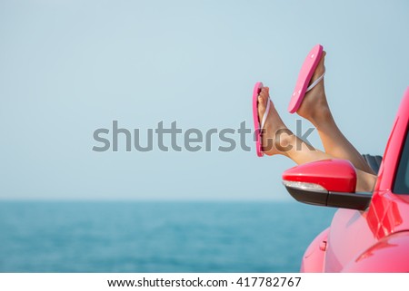 Young woman relaxing on the beach. Girl having fun in red cabriolet against blue sky background. Summer vacation and travel concept