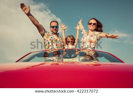 Happy family travel by car in the mountains. People having fun in red cabriolet. Summer vacation concept
