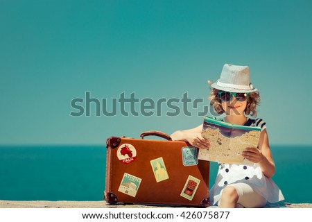 Child with vintage suitcase and city map on summer vacation. Travel and adventure concept